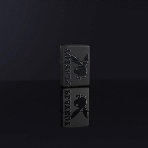 Lifestyle image of Playboy Logo Black Matte Windproof Lighter standing in a black reflective background