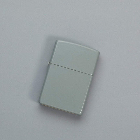 Lifestyle image of Flat Grey Windproof Lighter laying on a grey surface