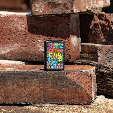 Lifestyle image of Zippo Street Art Design Black Matte Windproof Lighter standing on a brick with more bricks in the background