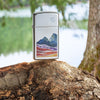 Lifestyle image of Slim® Landscape Design High Polish Chrome Windproof Lighter standing on a log in a forest.