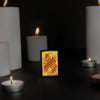 Lifestyle image of Flame and Dragon Black Matte Windproof Lighter standing with lit candles.