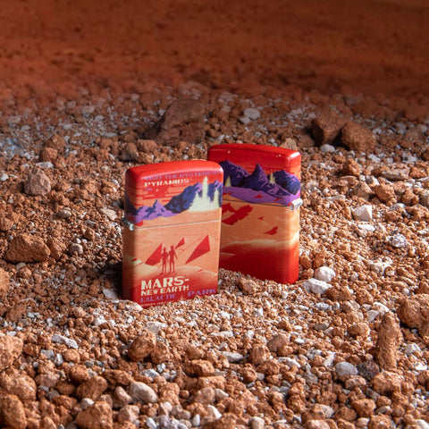 Lifestyle image of two Mars 540 Color Design Windproof Lighters standing on the Mars surface, one lighter showing the front of the design and the other showing the back.