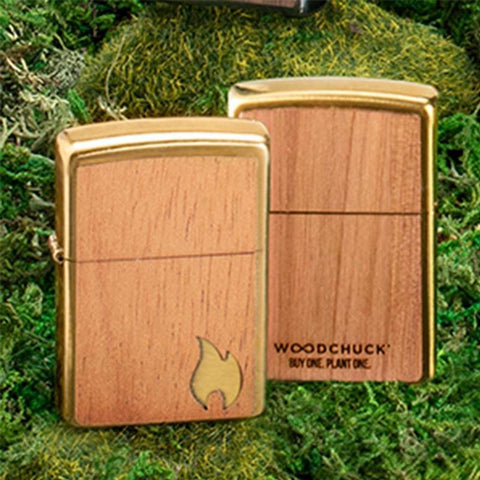 Lifestyle image of two Woodchuck USA Flame Lighters, one showing the front of the lighter and the other showing the back of the lighter on grass.