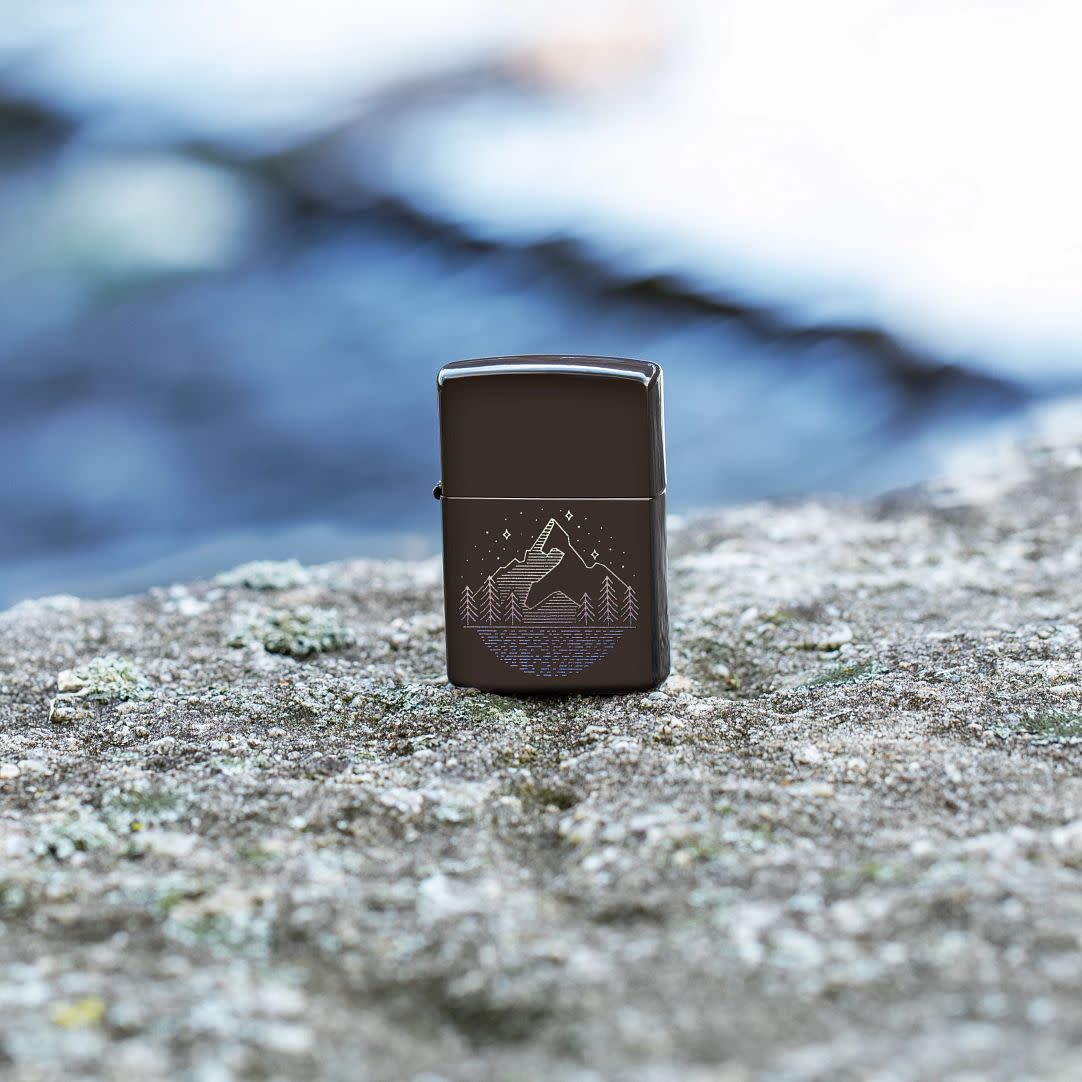 Lifestyle image of Mountain Design Brown Windproof Lighter standing on a rock.