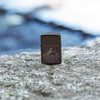 Lifestyle image of Mountain Design Brown Windproof Lighter standing on a rock.