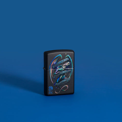 Lifestyle image of Anne Stokes Dragon Black Matte Windproof Lighter standing in a blue scene.