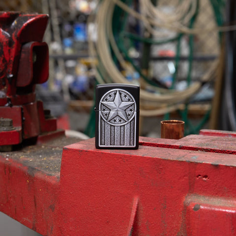 Lifestyle image of American Metal Emblem Black Matte Windproof Lighter standing in a garage.