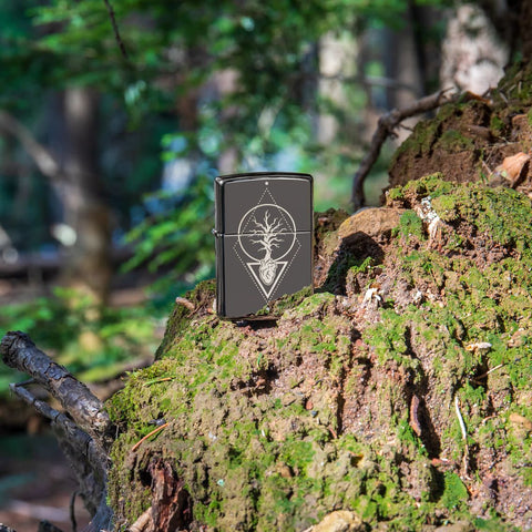 Lifestyle image of Heart Of Tree Design Black Ice® Windproof Lighter standing on a trees roots in the woods.