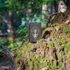 Lifestyle image of Heart Of Tree Design Black Ice® Windproof Lighter standing on a trees roots in the woods.