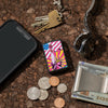 Lifestyle image of Lady Liberty Design Black Matte Windproof Lighter laying on a counter with a phone, keys, watch, change, and a money clip.