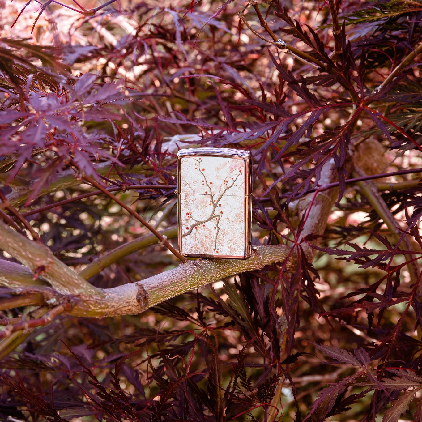 Lifestyle image Eastern Design Cherry Blossom High Polish Rose Gold Windproof Lighter standing in a tree.