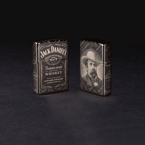 Lifestyle image of two Jack Daniel's® Photo Image 360® Black Ice® Windproof Lighters standing in a black background. One lighter is showing the front and the other is showing the back.