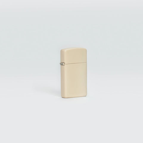 Lifestyle image of Slim® Flat Sand Windproof Lighter standing in a grey scene.