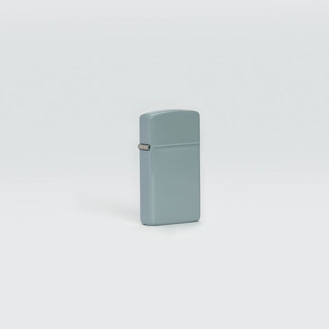 Lifestyle image of Slim® Flat Grey Windproof Lighter standing in a grey background.