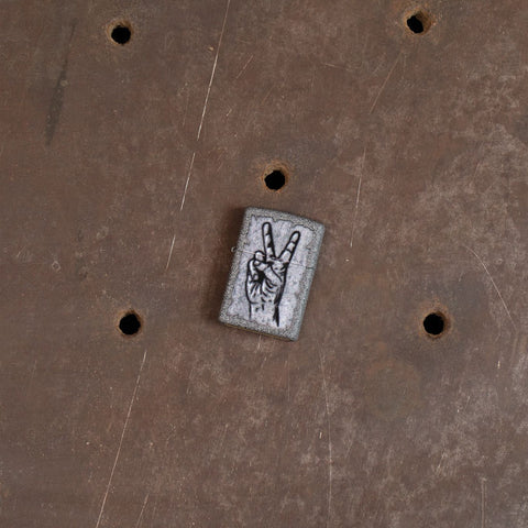 Lifestyle image of Graffiti Peace Design Iron Stone Windproof Lighter laying on an steel sewer cover