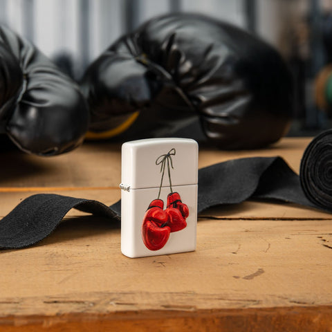 Lifestyle image of Boxing Design Texture Print White Matte Windproof Lighter with boxing gloves in the background.