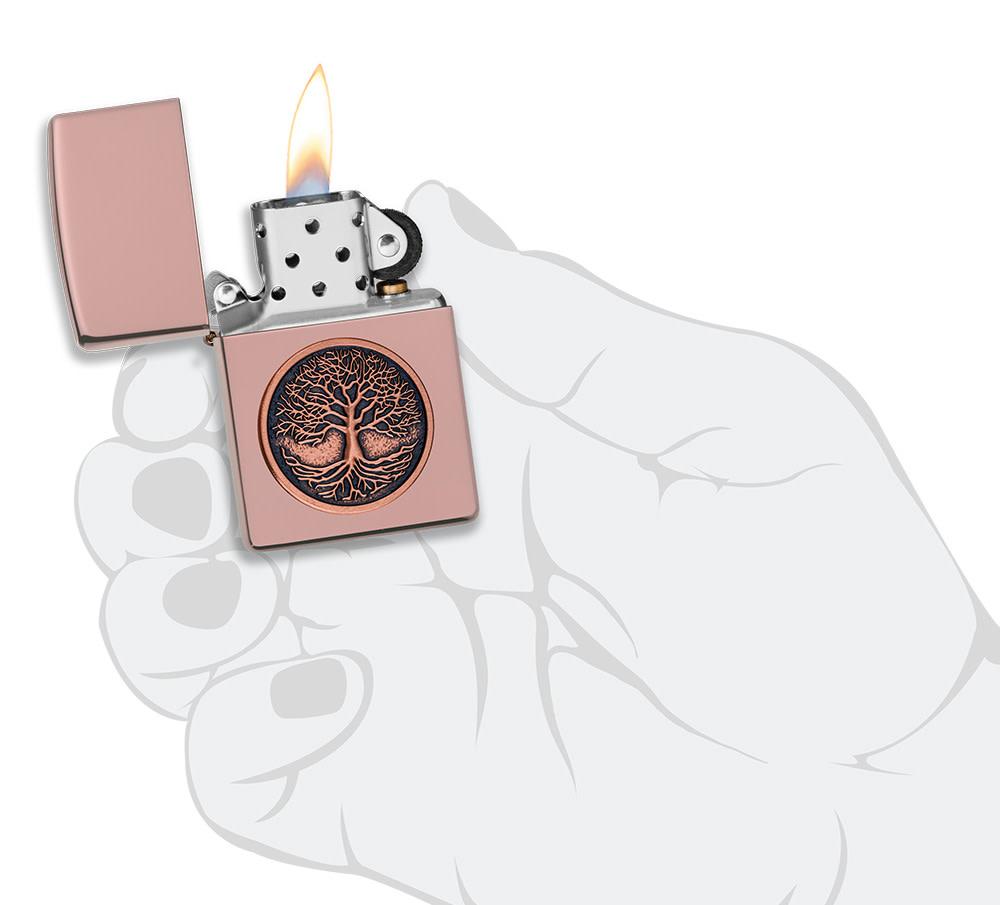 Tree of Life Emblem High Polish Rose Gold Windproof Lighter lit in hand.