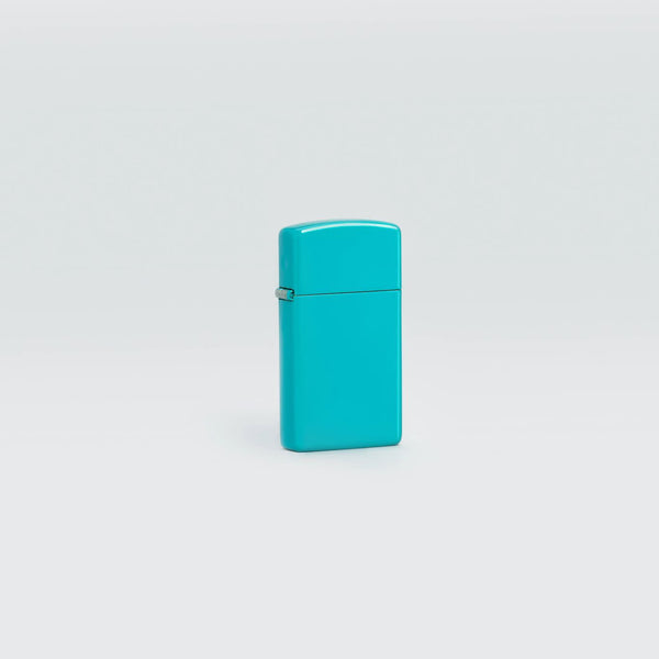 Lifestyle image of Slim® Flat Turquoise Windproof Lighter standing in a grey scene.