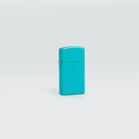 Lifestyle image of Slim® Flat Turquoise Windproof Lighter standing in a grey scene.